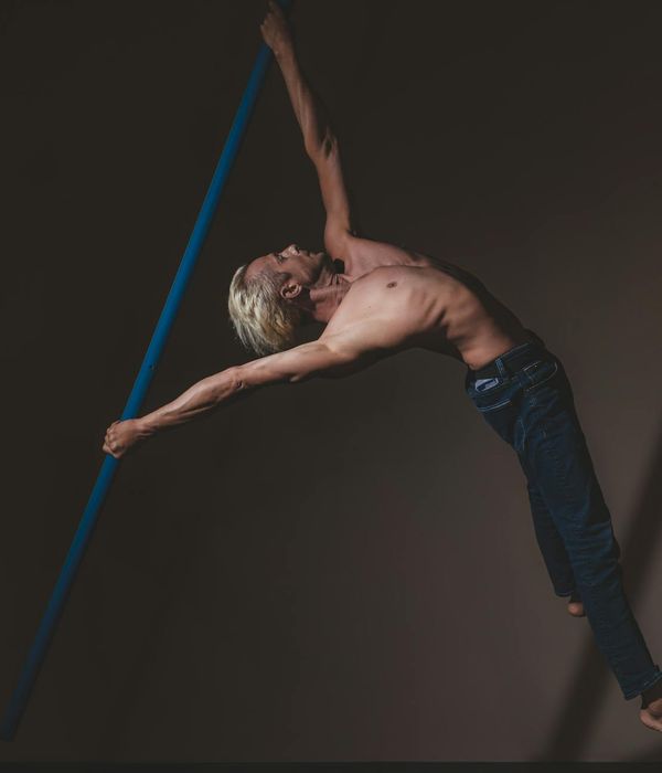 Man performing a controlled strength exercise in a dark room with cyan light.